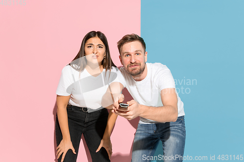 Image of Young emotional man and woman on pink and blue background