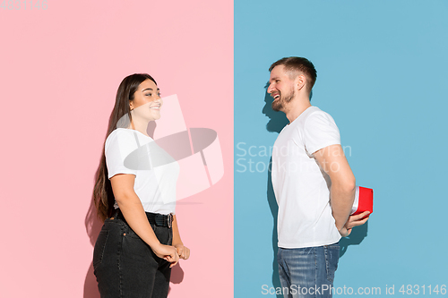 Image of Young emotional man and woman on pink and blue background