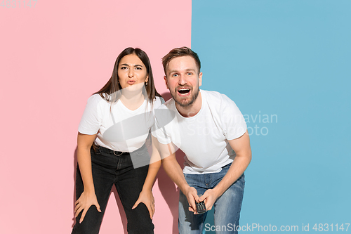 Image of Young emotional man and woman on pink and blue background