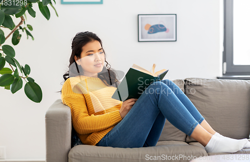 Image of asian young woman reading book at home