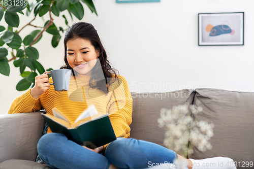 Image of woman reading book and drinking coffee at home