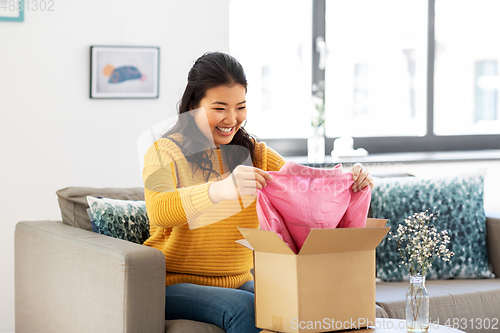 Image of happy asian young woman with parcel box at home