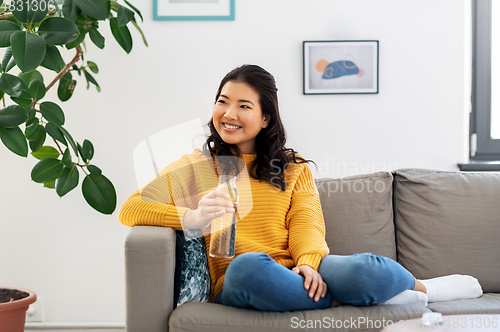 Image of smiling asian young woman drinking water at home