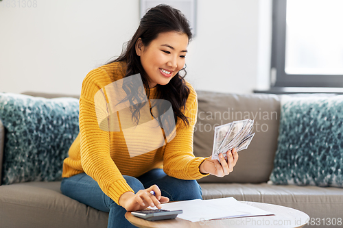 Image of woman with money, papers and calculator at home