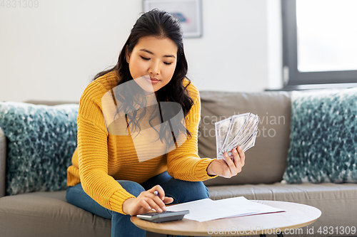 Image of woman with money, papers and calculator at home