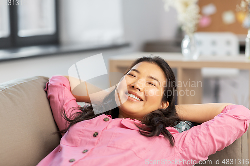 Image of happy asian woman lying on sofa and dreaming