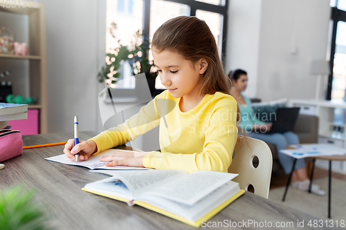 Image of student girl with book writing to notebook at home