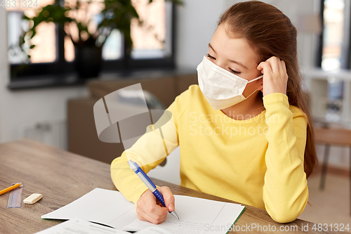 Image of bored sick girl in medical mask learning at home