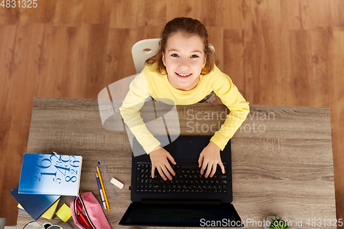 Image of smiling student girl typing on laptop at home
