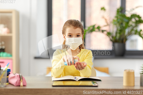 Image of sick girl in mask with hand sanitizer at home