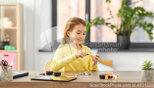 Image of happy girl playing with robotics kit at home