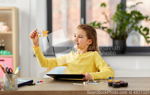 Image of girl with tablet pc and robotics kit at home