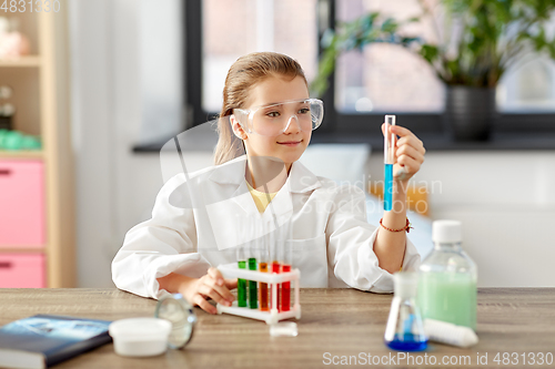 Image of girl with test tube studying chemistry at home