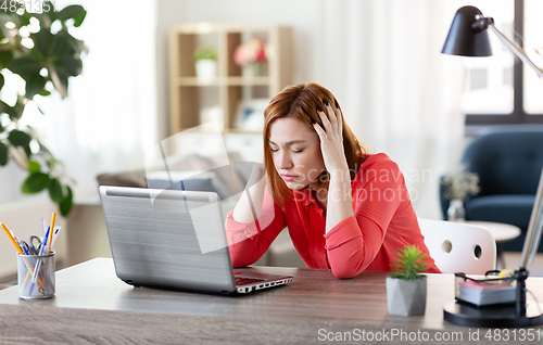 Image of stressed woman with laptop working at home office