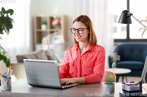 Image of happy woman with laptop working at home office