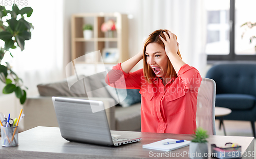 Image of angry woman with laptop working at home office