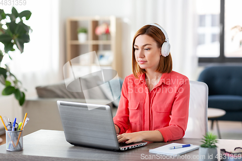 Image of woman in headphones with laptop working at home