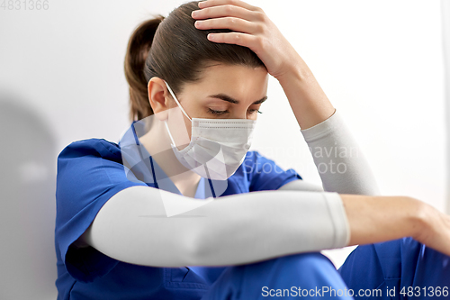 Image of sad doctor or nurse in face mask holding to head