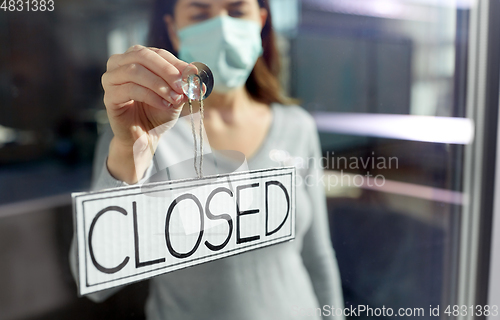 Image of woman in mask hanging banner closed on door