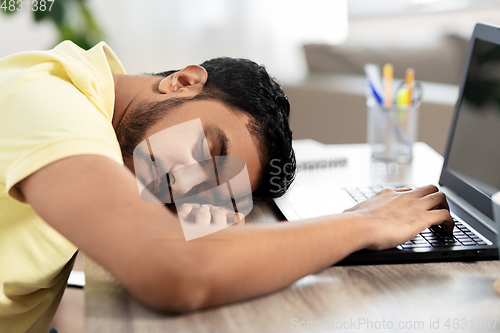 Image of indian man sleeping on table with laptop at home