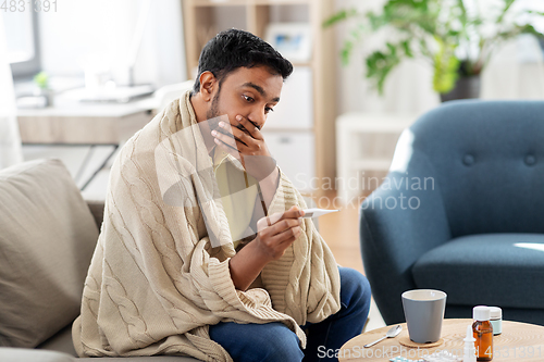 Image of sick man measuring temperature by thermometer