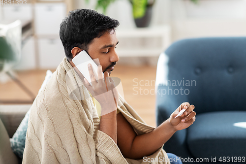 Image of sick man with thermometer calling on smartphone