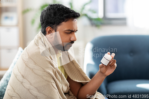 Image of sad sick man in blanket with medicine at home