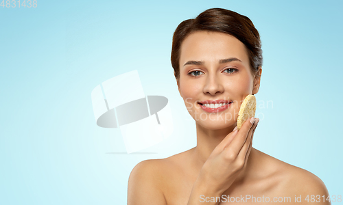 Image of young woman cleaning face with exfoliating sponge