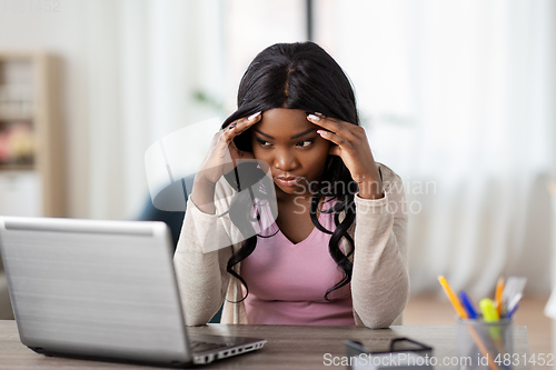Image of stressed woman with laptop working at home office