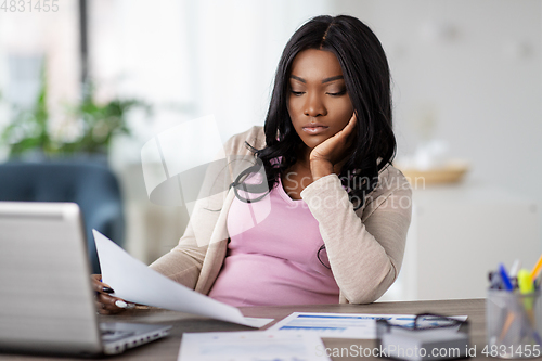 Image of bored woman with papers working at home office