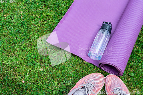 Image of Sneakers, water bottle and a purple fitness mat. Sport concept