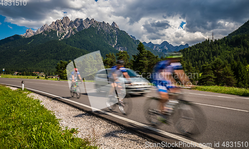 Image of Cyclists riding a bicycle on the road in the background the Dolo