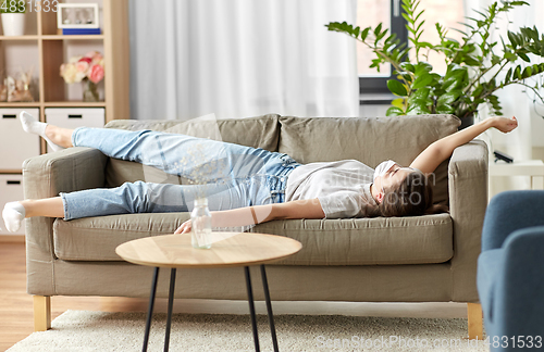 Image of sick woman in medical mask lying on sofa at home