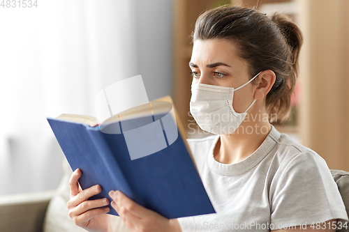 Image of sick woman in medical mask reading book at home