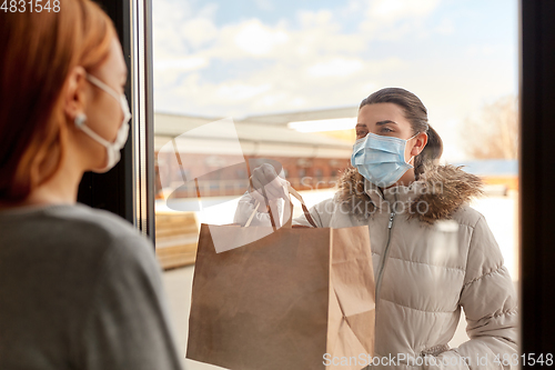 Image of woman in medical mask delivers food for her friend