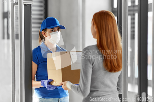 Image of delivery girl in face mask giving parcel to woman