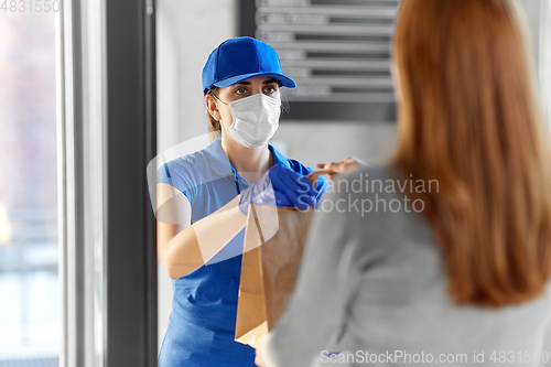 Image of delivery girl in mask giving paper bag to woman