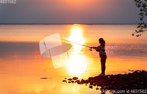 Image of Woman fishing on Fishing rod spinning in Finland at sunset.