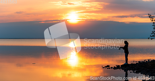 Image of Woman fishing on Fishing rod spinning in Finland at sunset.