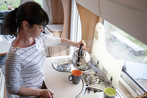 Image of Woman cooking in camper, motorhome interior