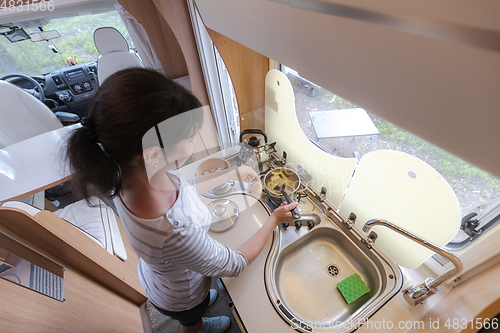 Image of Woman cooking in camper, motorhome interior