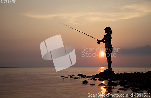 Image of Woman fishing on Fishing rod spinning in Finland at sunset.