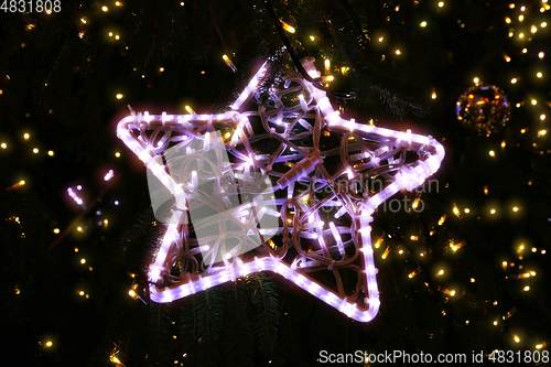 Image of Bright beautiful glowing star on a Christmas tree in the evening