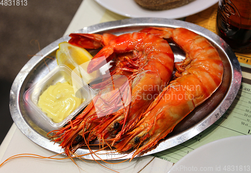 Image of Jumbo shrimps with lemon and sauce on metal plate