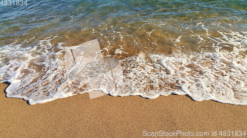 Image of Sea wave with white foam on the sandy beach