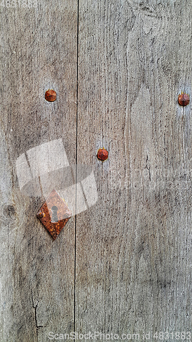 Image of Vintage wooden door with rusty keyhole and rivets