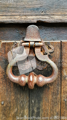 Image of Vintage doorknocker close-up on weathered wooden door texture