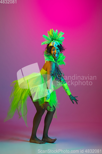 Image of Beautiful young woman in carnival and masquerade costume on gradient studio background in neon light