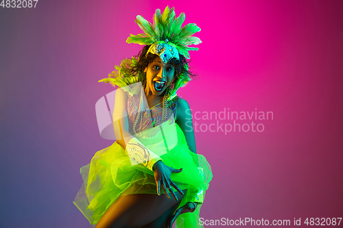 Image of Beautiful young woman in carnival and masquerade costume on gradient studio background in neon light