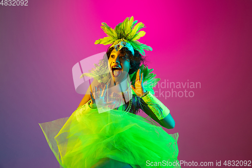 Image of Beautiful young woman in carnival and masquerade costume on gradient studio background in neon light